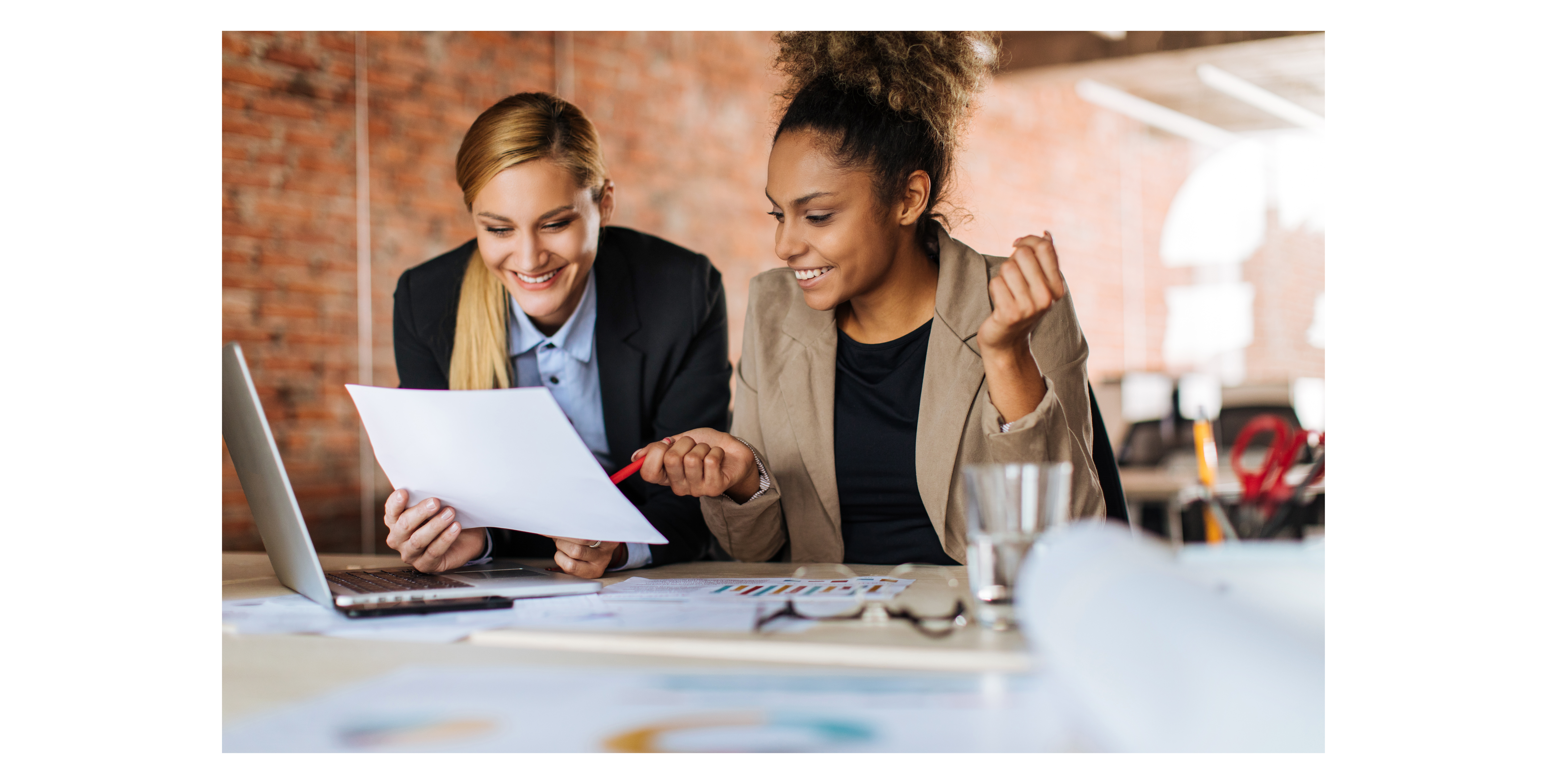 Deux femmes souriant, regardant un document. L'une d'entres elles est un consultant en marketing